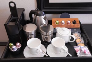 A breakfast tray with coffee makers, kettles, cups, and pastries.