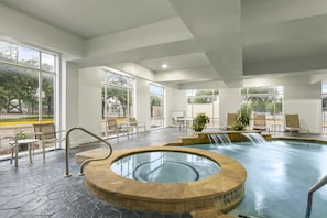 Una piscina interna con idromassaggio, zona relax e ampie finestre.