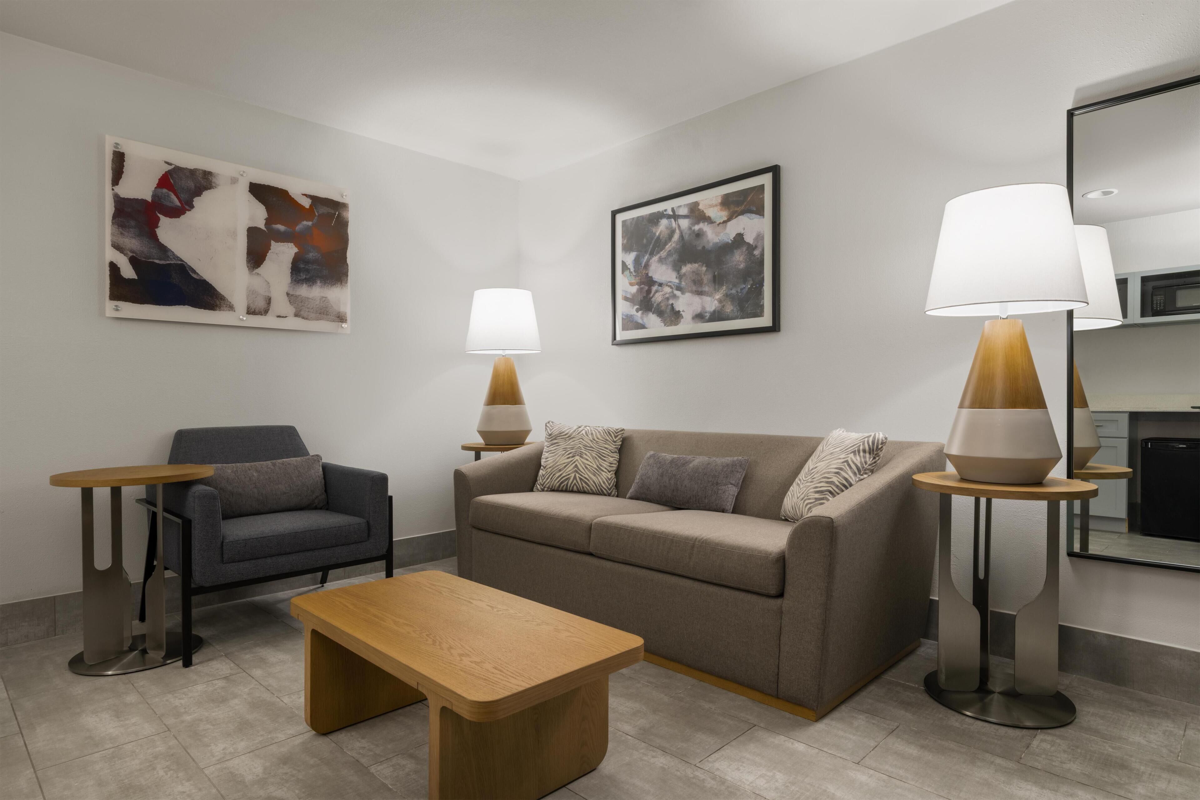 A modern living room with a sofa, two side tables, a coffee table, and two lamps.