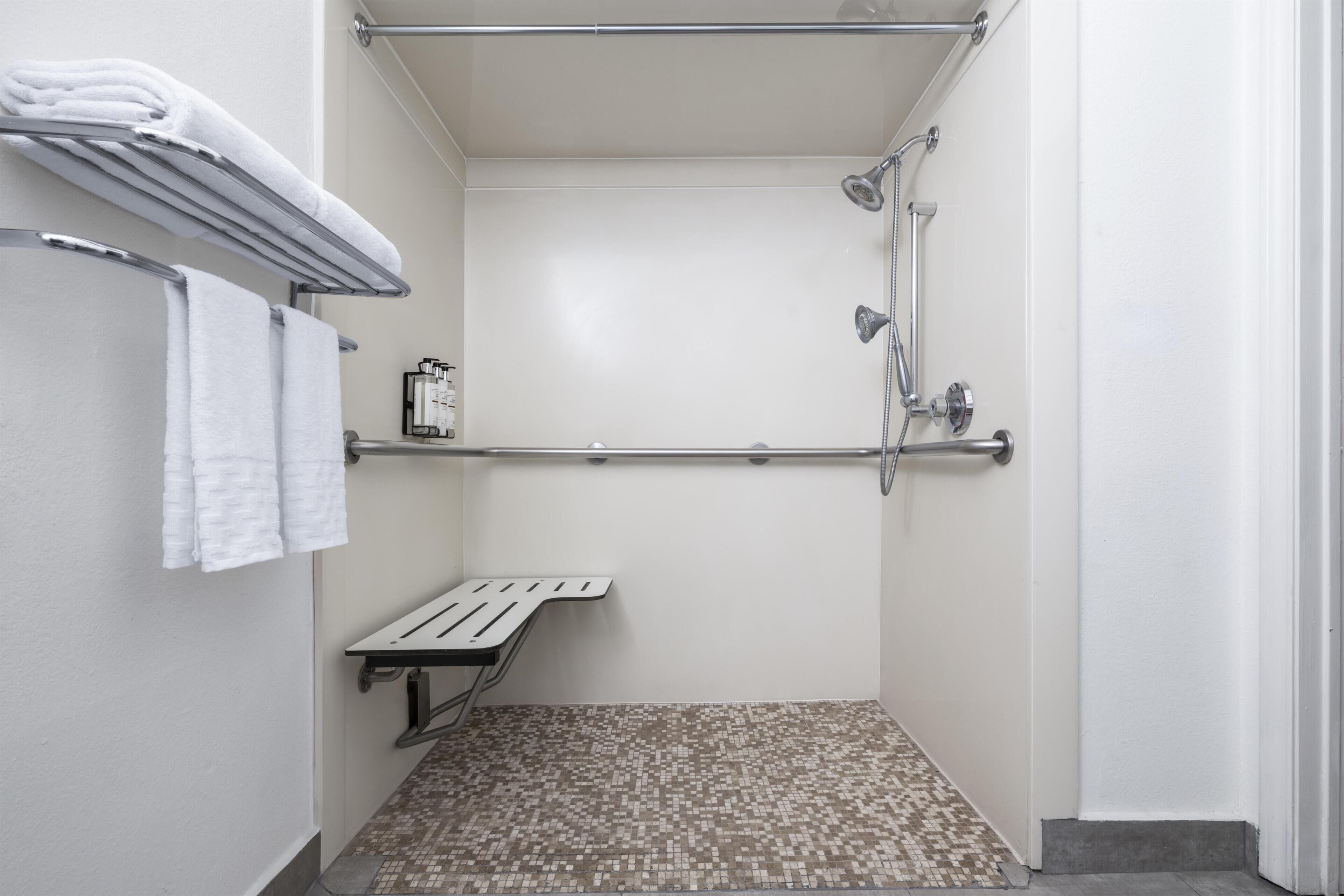 A small, enclosed shower area with a metal shelf, a towel rack, and a showerhead.