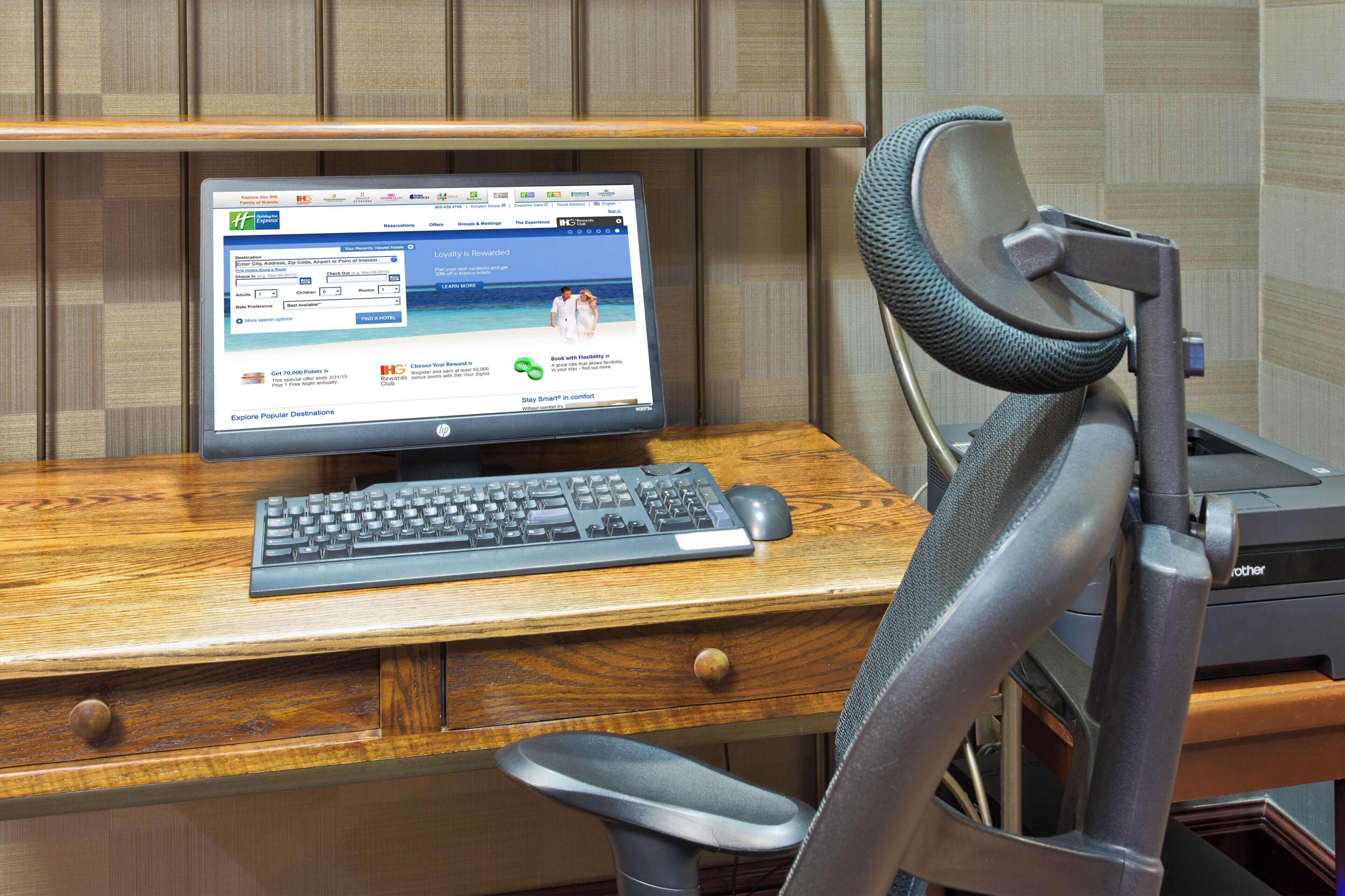 A wooden desk with a desktop computer, a keyboard, and a mouse.