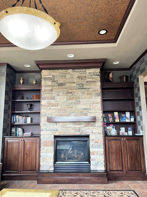 A living room with a stone fireplace, wooden bookshelves, and a hanging light fixture. - Holiday Inn Express Hotel & Suites Portland-NW Downtown by IHG (Portland)