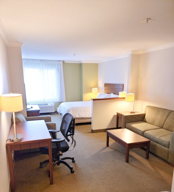 A hotel room with a bed, a desk, a chair, a sofa, and two lamps. - Holiday Inn Express Hotel & Suites Portland-NW Downtown by IHG (Portland)