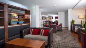 A modern hotel lobby with leather seating, a wooden reception desk, and a patterned carpet. - Holiday Inn Express Swindon - West by IHG (Swindon)