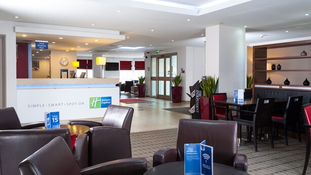 A hotel lobby with a reception desk, seating area, and a dining section. - Holiday Inn Express Swindon - West by IHG (Swindon)