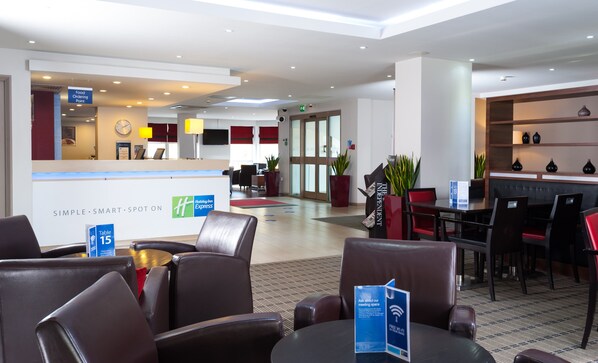 Un vestíbul d'hotel amb una recepció, zona de seients i una zona de dinar.