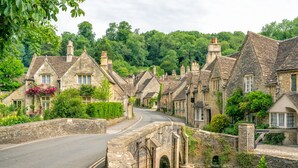A stone bridge over a river, surrounded by traditional stone houses with chimneys, a curved road, and lush greenery. - Holiday Inn Express Swindon - West by IHG (Swindon)