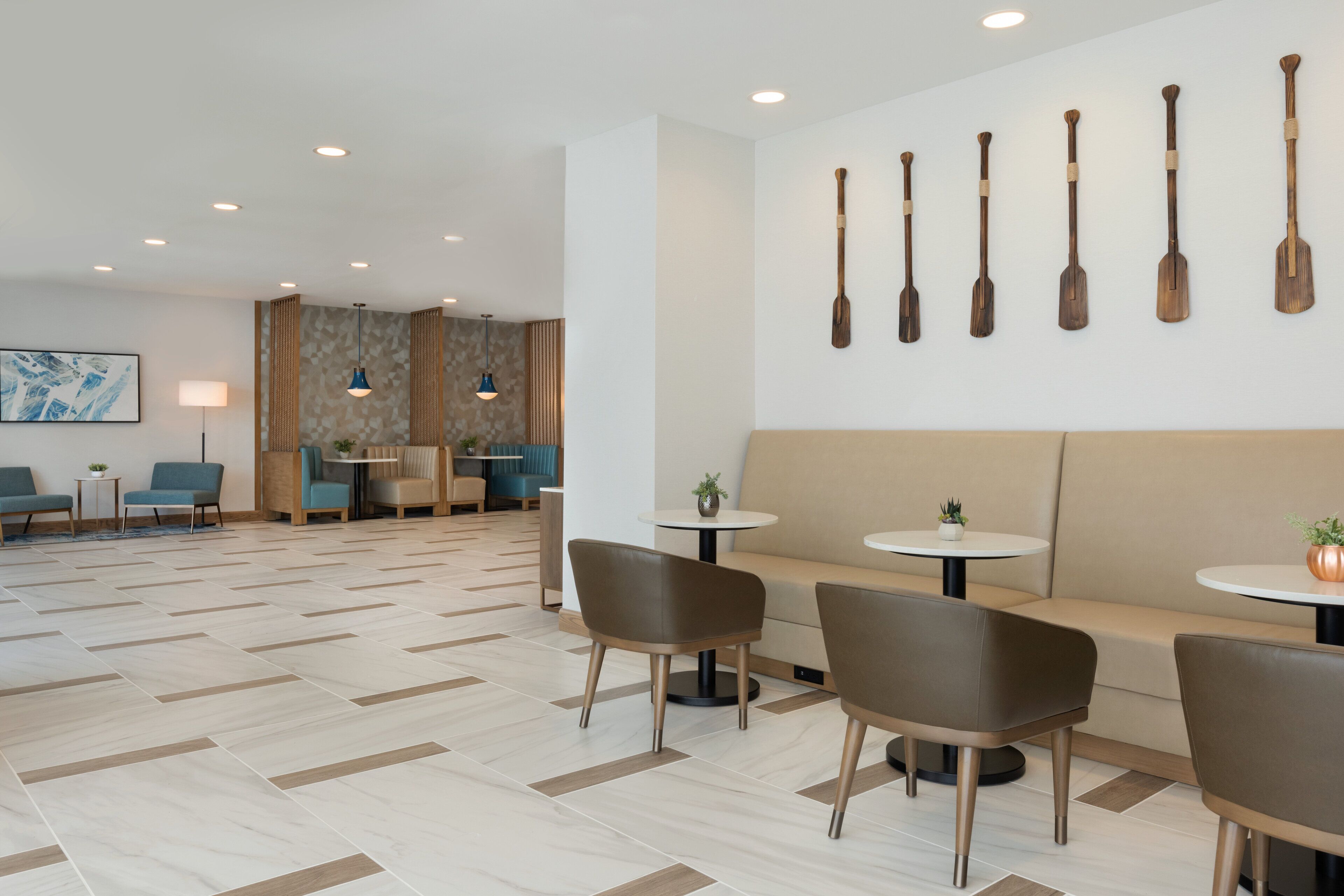Eine moderne Hotellobby mit Sitzgelegenheiten, Tischen und einer Wand mit Paddleboards.