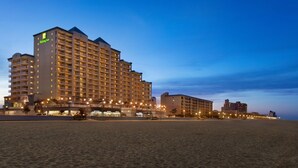 A large hotel with multiple floors and balconies, situated on a beach with a clear sky. - Holiday Inn & Suites Ocean City by IHG (Ocean City)