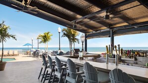 A beachside bar with Adirondack chairs, a pool, and a view of the ocean. - Holiday Inn & Suites Ocean City by IHG (Ocean City)