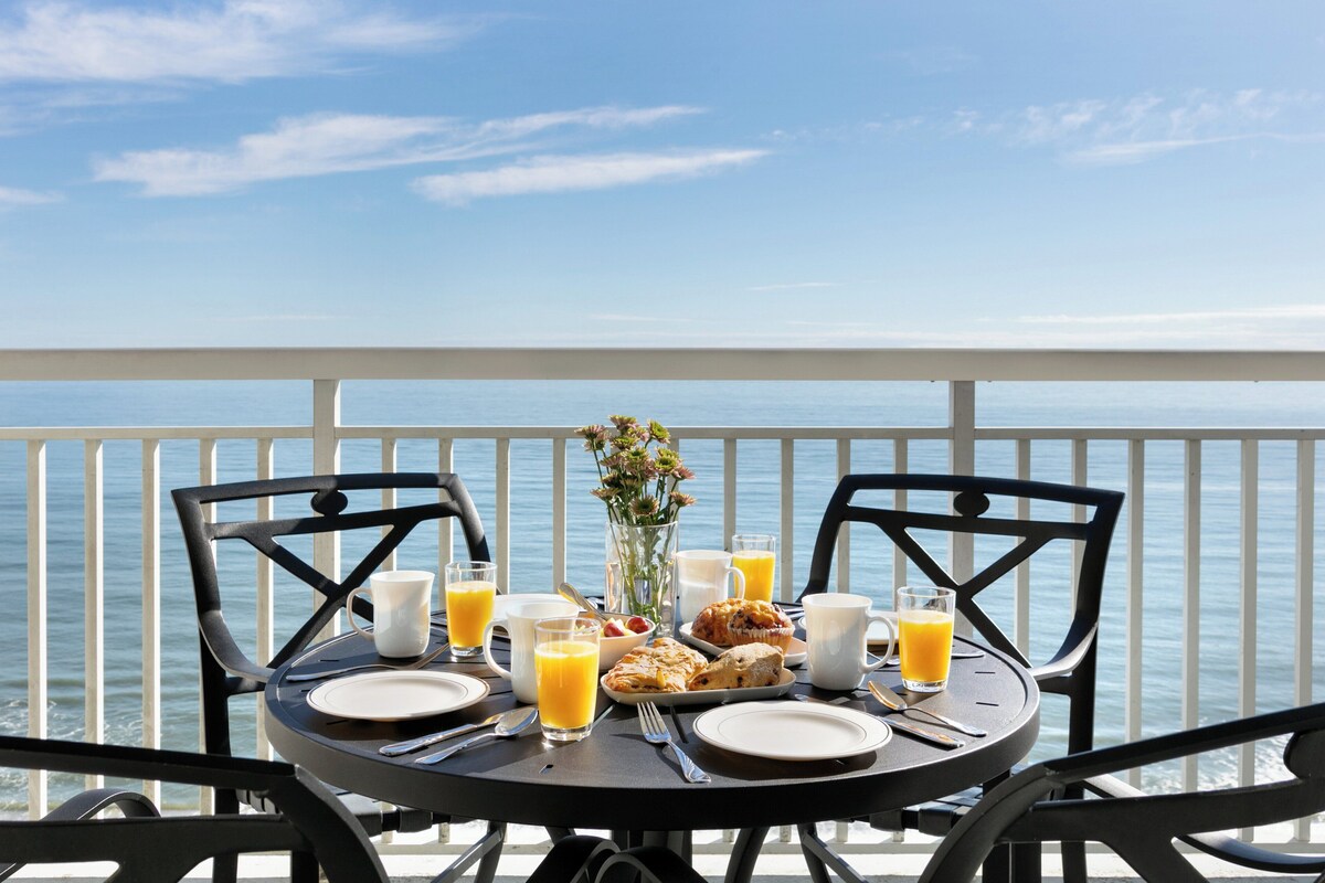 A table set for breakfast with a view of the sea.
