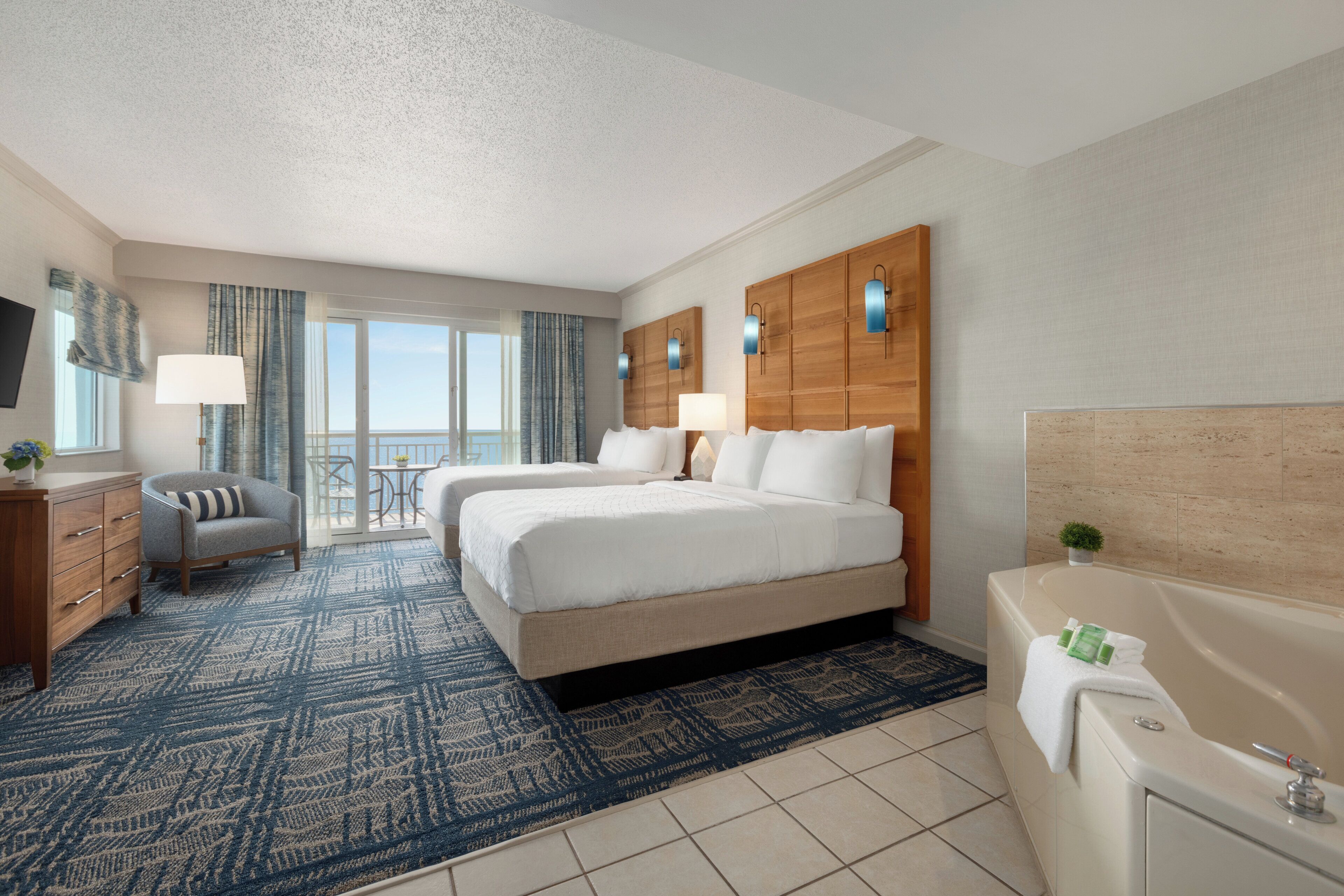 Une chambre d’hôtel avec un grand lit, un bureau, une chaise, une salle de bain et une vue sur l’extérieur.
