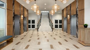 A spacious hallway with a marble floor, wooden paneling, and a central staircase. - Holiday Inn & Suites Ocean City by IHG (Ocean City)