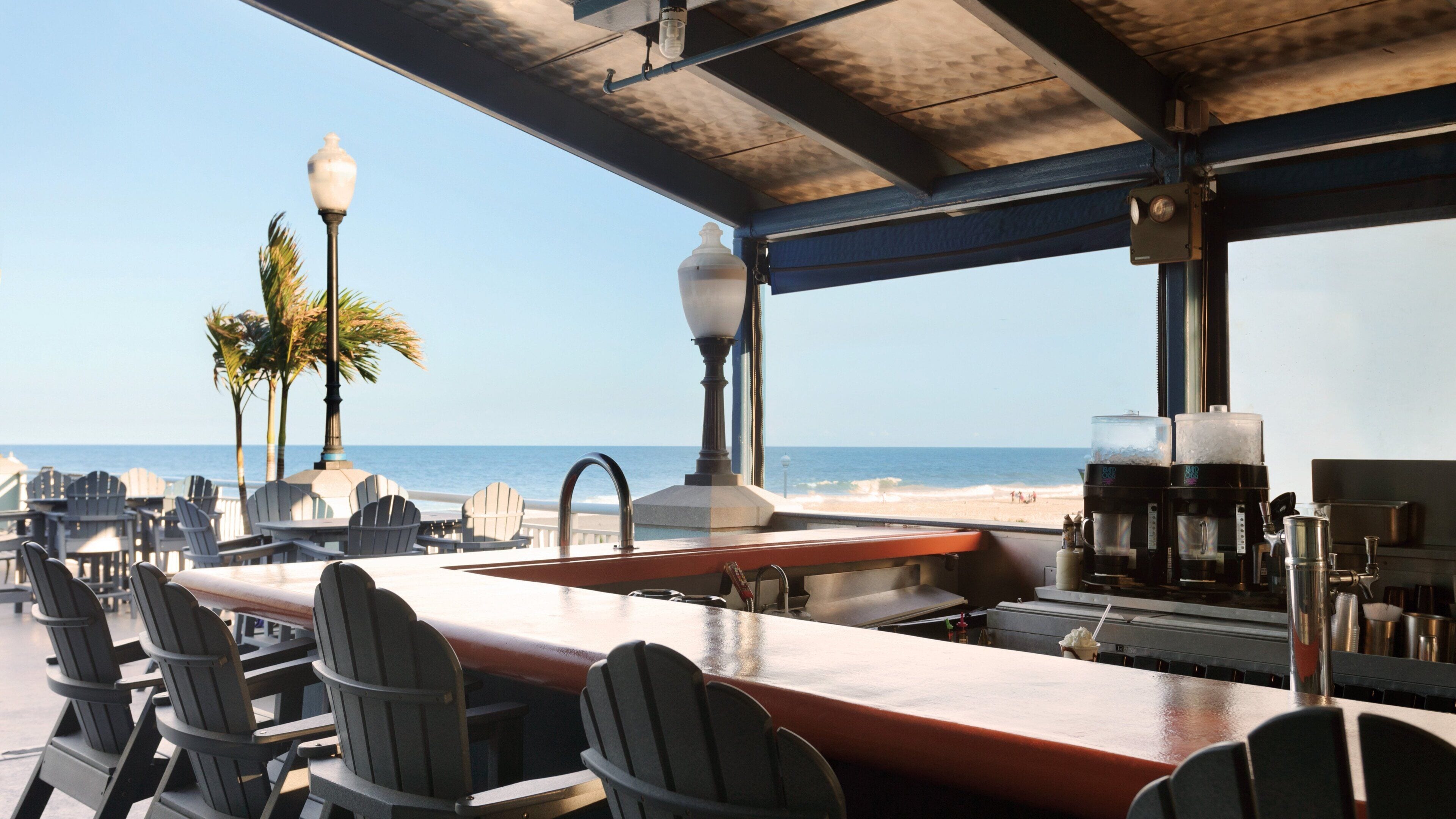 Um bar à beira-mar com área externa, vista para o oceano e uma máquina de café.