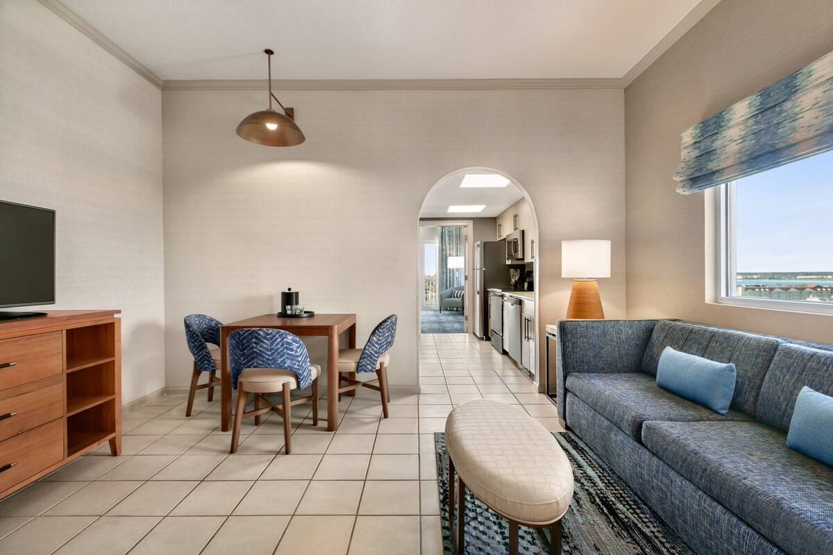 A modern living room with a sofa, TV, dining table, and chairs.
