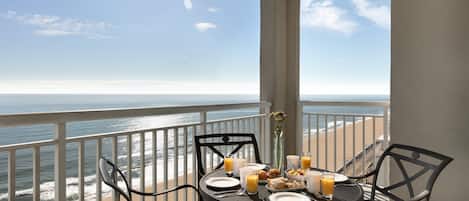 Una mesa en el balcón con alimentos para el desayuno y vista al océano.