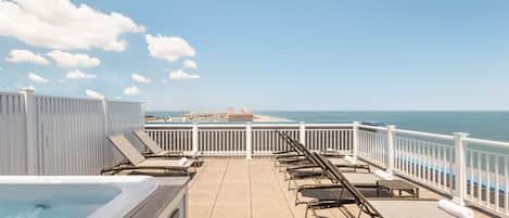 Une terrasse avec des chaises longues et un jacuzzi donnant sur l’océan.