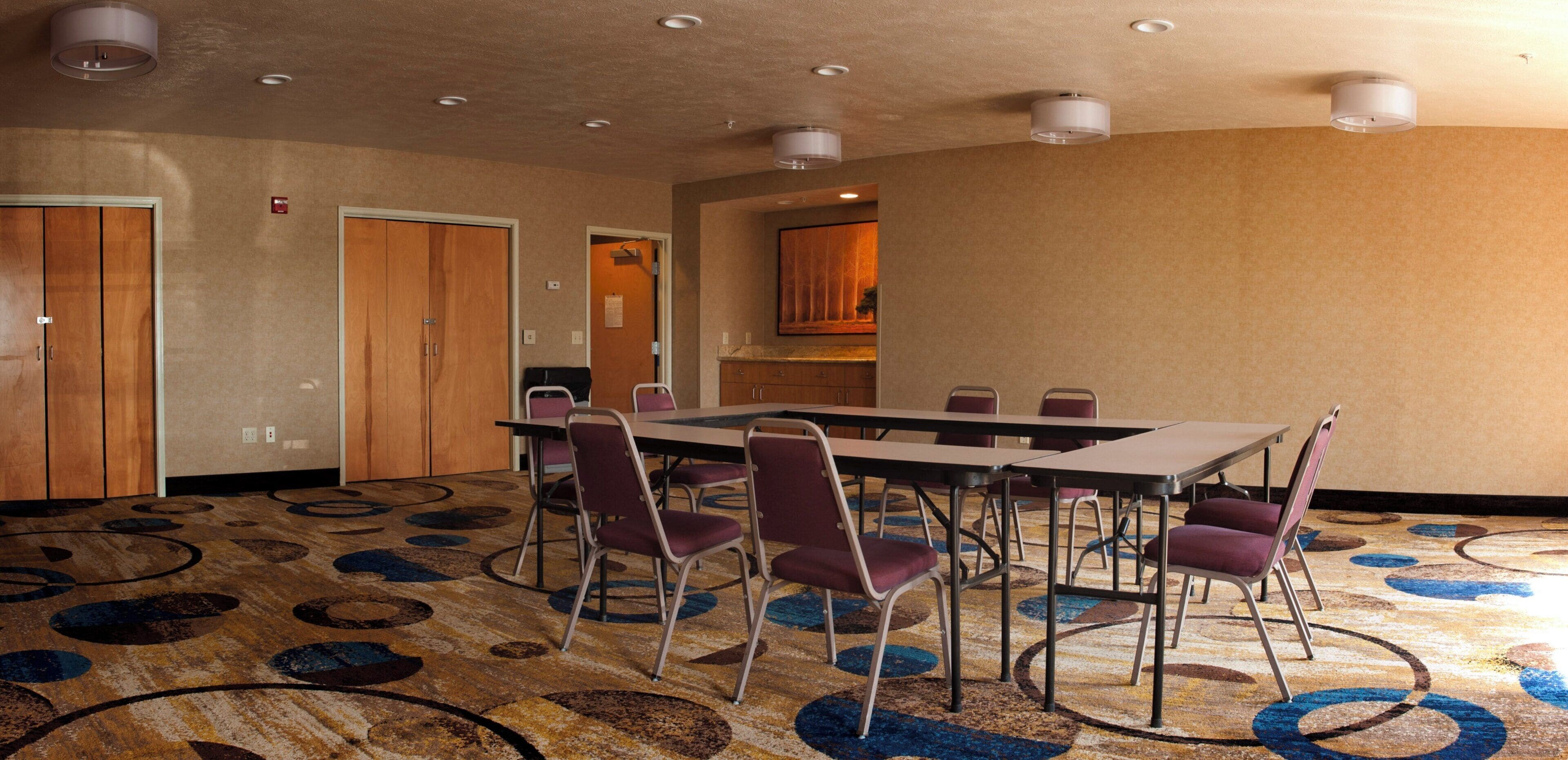 A conference room with a long table, chairs, and a carpeted floor.