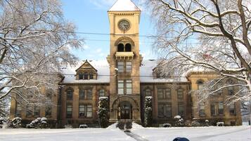 A historic building with a clock tower, arched windows, and snow-covered surroundings.