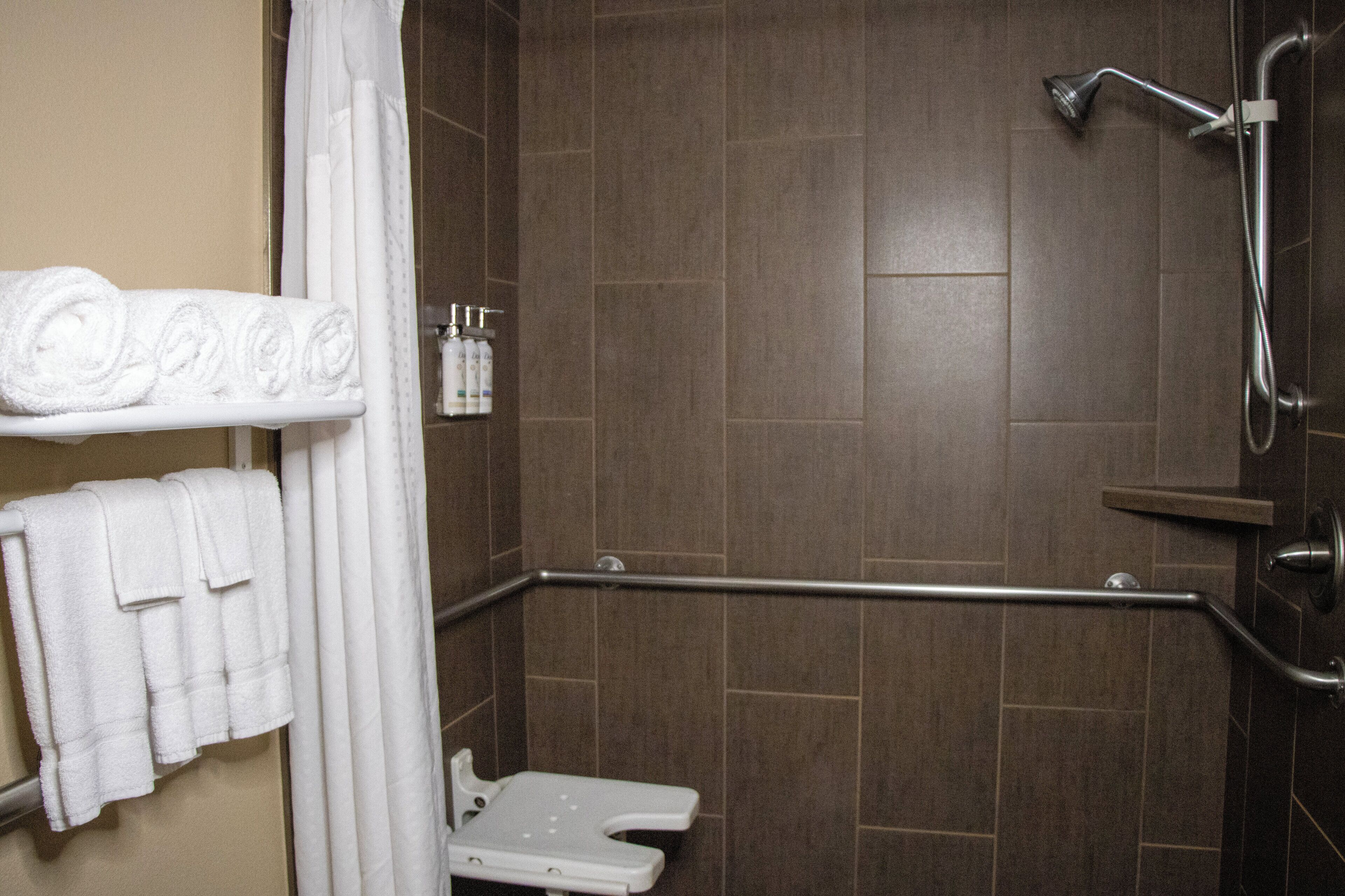 A bathroom with a shower, a toilet, and a towel rack with towels.