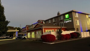 A Holiday Inn Express building with a stone facade, multiple windows, and a parking lot with vehicles.