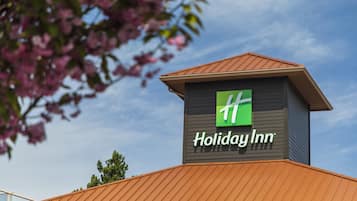 Een Holiday Inn bord op een gebouw met een bruin dak en een heldere lucht.