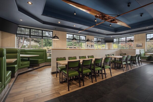 A restaurant with green booths, wooden tables, and chairs.