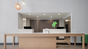 A reception desk with a modern design, a logo on the wall, and a wooden floor.
