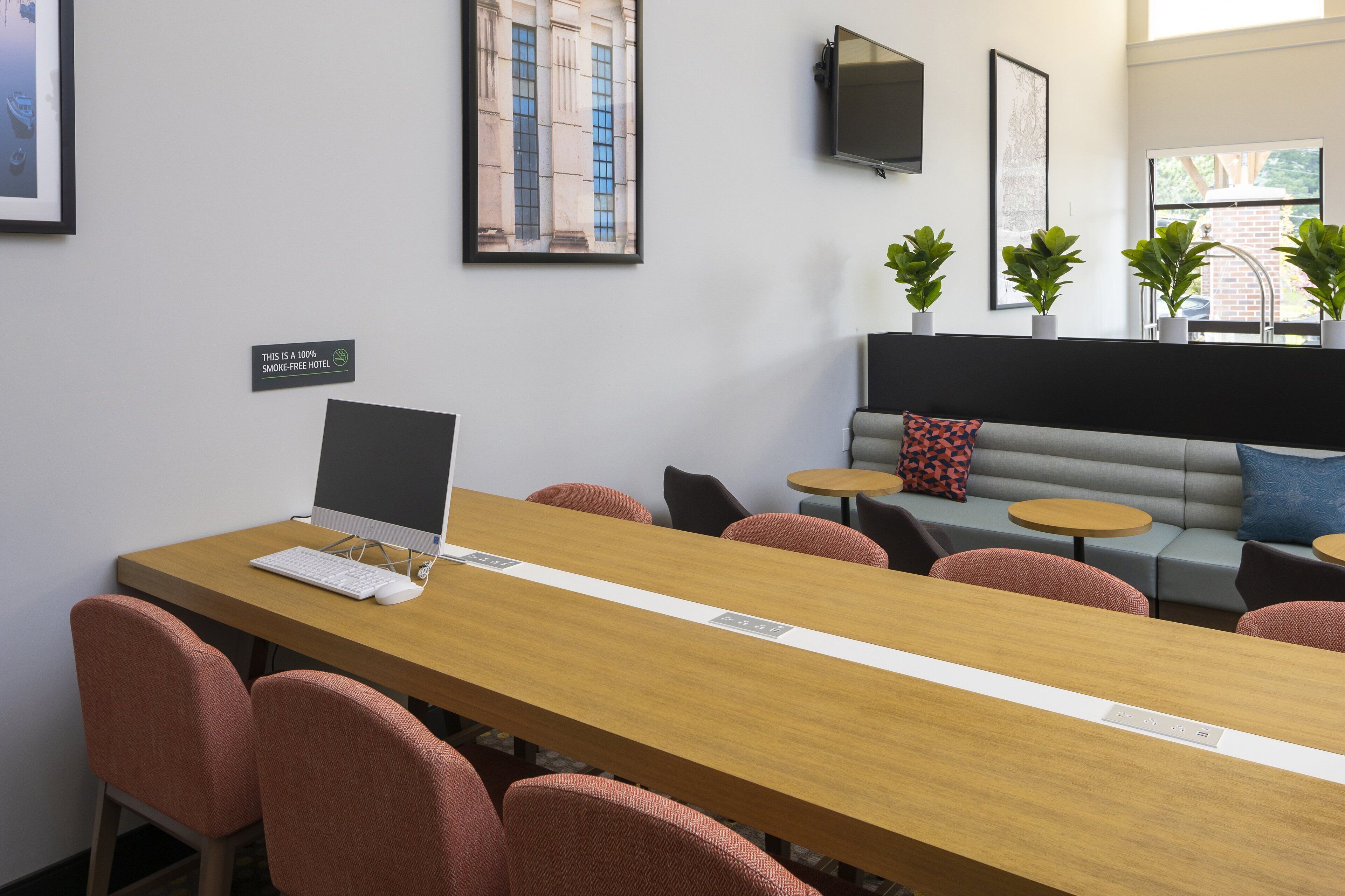 A conference room with a long table, several chairs, a computer, and a sofa with cushions.