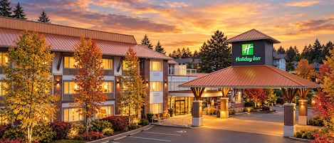 Un hôtel Holiday Inn doté d’une entrée couverte, d’un parking et entouré d’un paysage automnal aux couleurs flamboyantes.