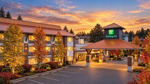 A Holiday Inn hotel with a covered entrance, parking lot, and autumn foliage. - Holiday Inn Victoria Elk Lake by IHG (Victoria)