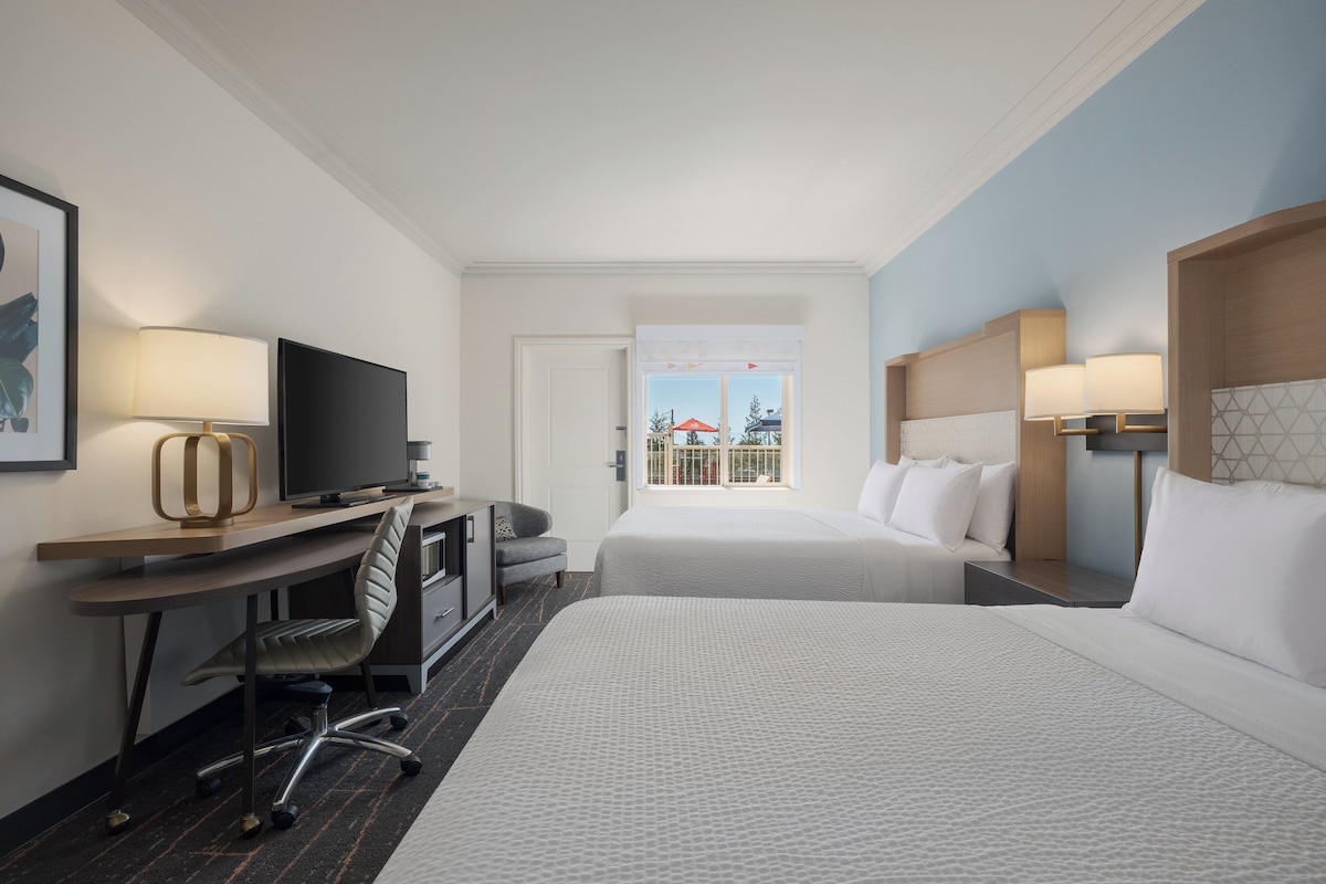 A hotel room with a bed, desk, chair, TV, and a window with a view.