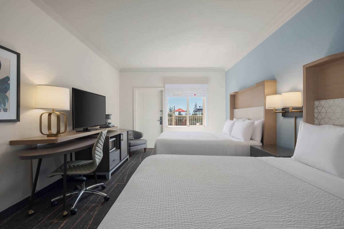 Habitación de hotel con cama, escritorio, silla, televisión y ventana con vistas.