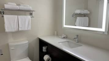 A modern bathroom with a white toilet, a sink with a mirror, and towel racks.
