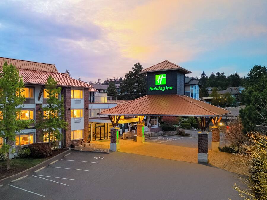 A Holiday Inn hotel with a parking lot, multiple buildings, and a clear sky.