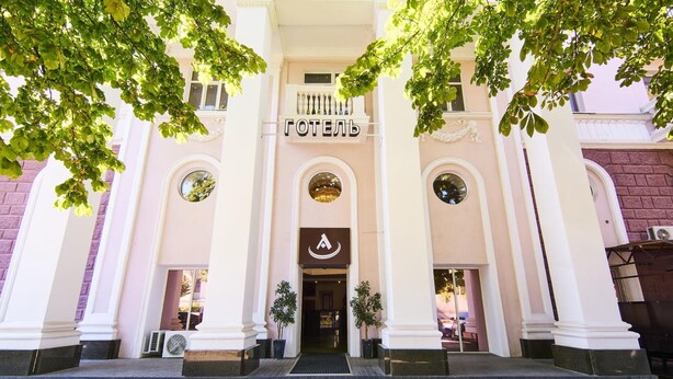 L’entrée d’un hôtel, avec une enseigne indiquant « HÔTEL » et un logo au-dessus de la porte.