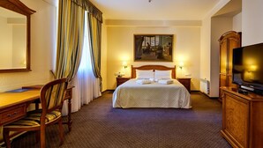 Une chambre d’hôtel avec un lit, un bureau, une chaise, une télévision et un tableau au mur.