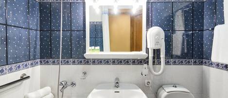 A bathroom with a white sink, a toilet, and a shower.