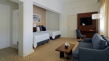 Una habitación de hotel con dos camas, un sofá, un televisor y una lámpara.
