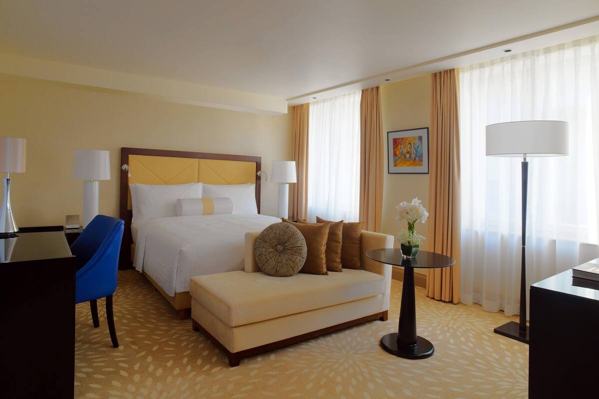 Ein Hotelzimmer mit Bett, einer Couch, einem Schreibtisch und einer Lampe.