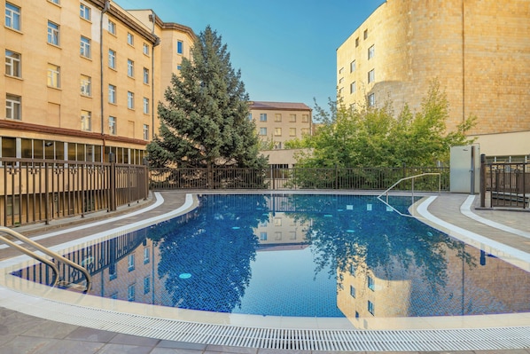 Una piscina al aire libre de temporada, sombrillas