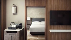 A hotel room with a bed, a TV, a desk with a lamp, and a minibar. - Armenia Marriott Hotel Yerevan (Yerevan)