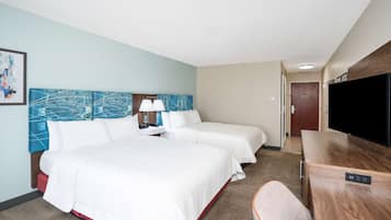 A hotel room with a large bed, two bedside tables, a TV, and a desk.
