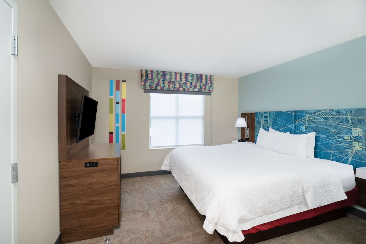 Een hotelkamer met een bed, een televisie, een bureau en een raam met uitzicht.