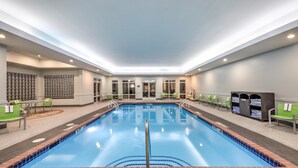 A large indoor pool with clear blue water, surrounded by lounge chairs and a seating area. - Hampton Inn & Suites by Hilton West Little Rock (Little Rock)