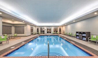 Una amplia piscina interior con agua cristalina, rodeada de sillones de descanso y una zona de estar.