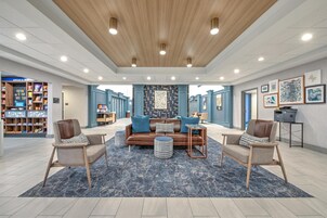 Un amplio salón con diseño moderno, que incluye un sofá central, dos sillones, una mesa de centro y una alfombra estampada.