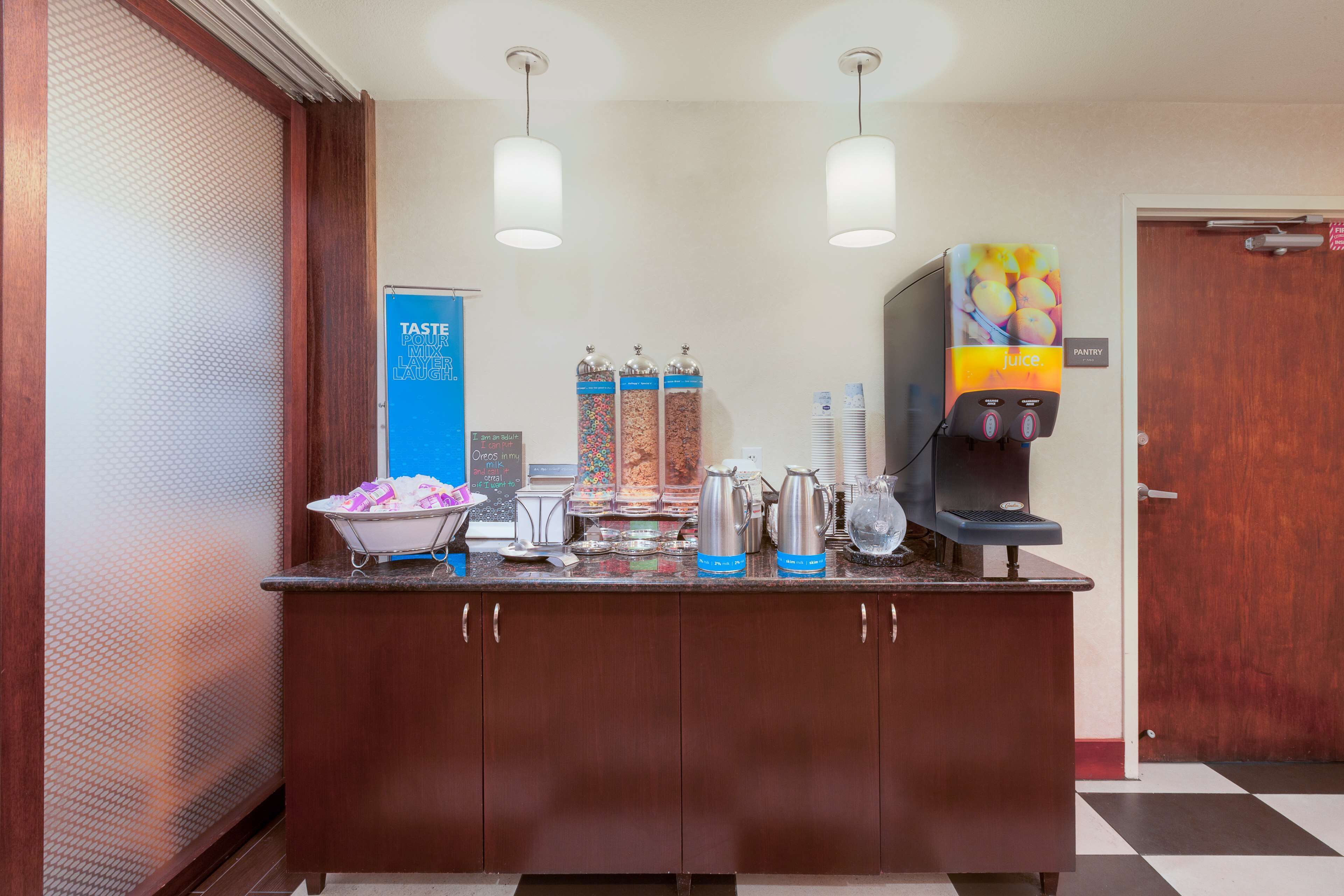 A breakfast bar with a coffee machine, condiment dispensers, and a juice dispenser.