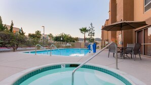 Een zwembadgedeelte met een jacuzzi, buitenmeubilair en een overdekt terras.
