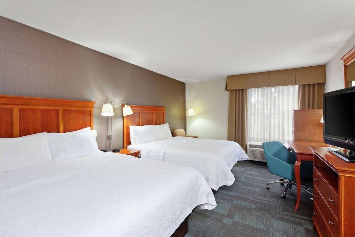 Habitación de hotel con dos camas, un escritorio con televisor y una silla.
